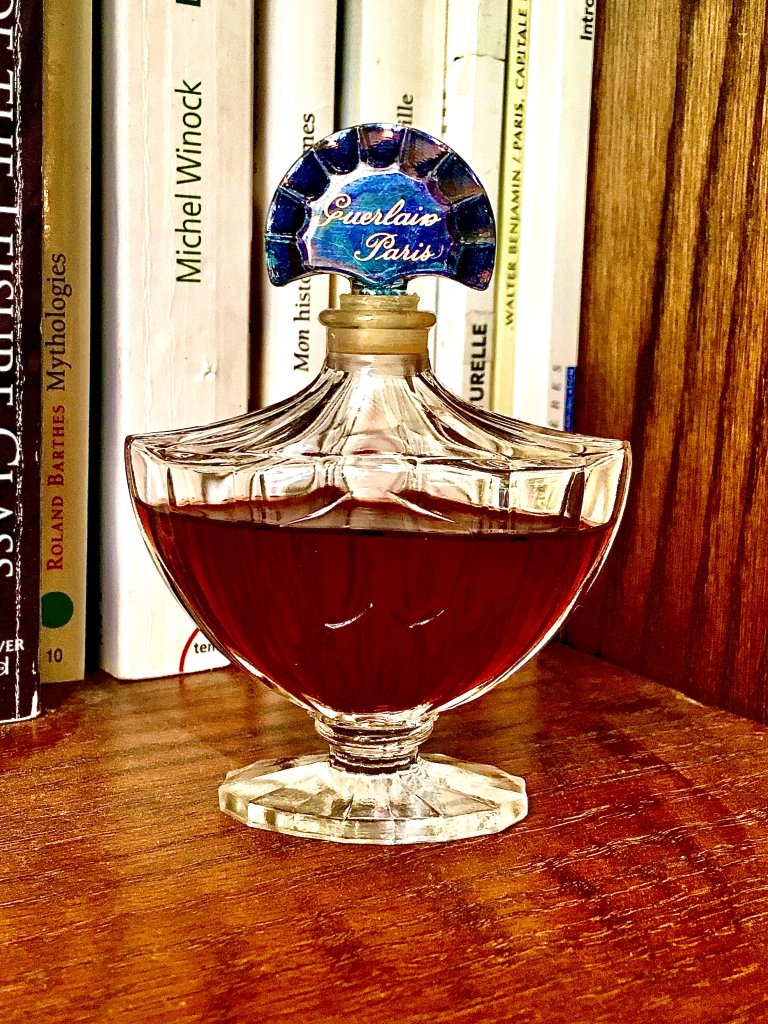 A bottle sitting on a book shelf