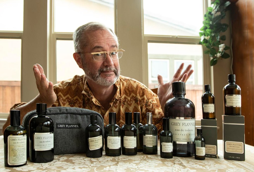 Paul Kiler sitting behind a larger collection of vintage Grey Flannel perfume bottles